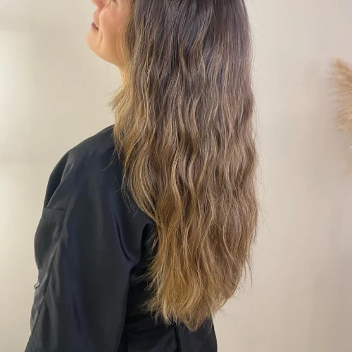 Vista a pelo ondulado con highlights de una cliente