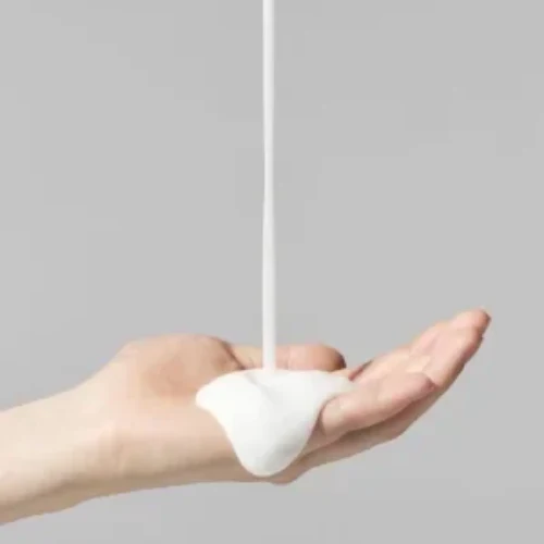 Producto para cabello que cae en un chorro sobre una mano